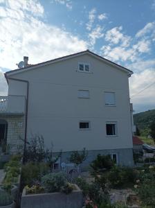 a large white building with some plants in front of it at Feel Good Apartment Rab Mundanije 131 in Mundanije