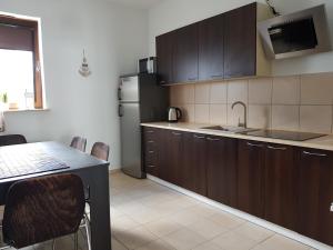 kuchnia z drewnianymi szafkami, stołem i lodówką w obiekcie Apt with 6 single beds w Świnoujściu