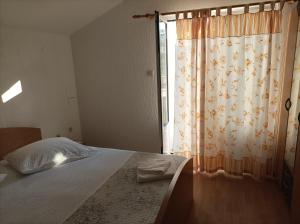 a bedroom with a bed with a curtain and a window at Feel Good Apartment Rab Mundanije 131 in Mundanije