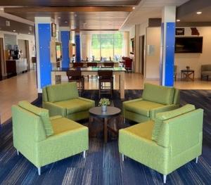 華倫斯堡的住宿－Holiday Inn Express & Suites Warrensburg North, an IHG Hotel，大堂设有两张绿色椅子和一张桌子