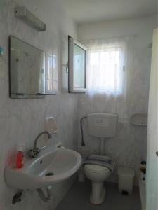 a bathroom with a sink and a toilet and a mirror at Elli Studios & Apartments in Marathokampos