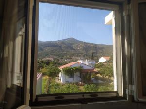 a window with a view of a house and a mountain at Elli Studios & Apartments in Marathokampos