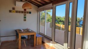 Zimmer mit einem Tisch und einem Balkon mit Fenstern in der Unterkunft Villa en bord de mer face à l'Ile de Porquerolles in Hyères