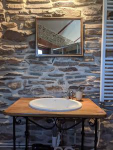 a bathroom sink with a mirror on a stone wall at Casa rural El Arroyo in Migueláñez