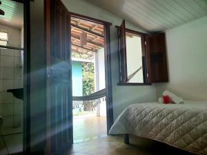 a bedroom with a bed next to a window at Pousada Corais Do Sul in Caraíva