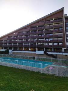 un edificio con una pista de tenis delante en Studio Le Lacuzon avec piscine et tennis extérieurs en Les Rousses