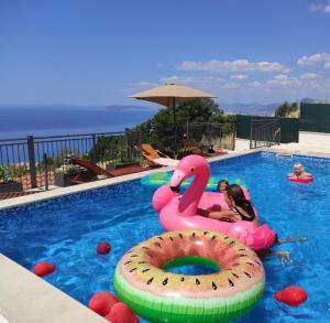 une fille dans une piscine avec un cygne rose dans une piscine dans l'établissement Kuća za odmor R&A, à Podstrana