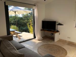 a living room with a couch and a television and a patio at Villa Catharina in Lorgues