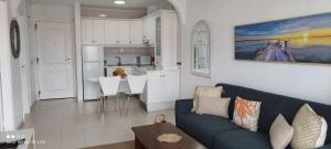 a living room with a blue couch and a kitchen at Precioso apartamento con piscina junto al mar in Costa Del Silencio