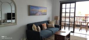 a living room with a blue couch and a table at Precioso apartamento con piscina junto al mar in Costa Del Silencio