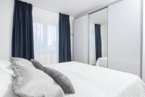 una camera da letto con letto bianco, cuscini e specchio di Apartment Kiki a Kaštel Štafilić