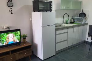 cocina con nevera blanca y TV en FAVORITE COMFORT, en Beer Sheva