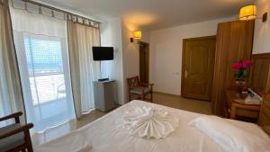 a bedroom with a white bed and a television at Sor Inn Holiday in Eforie Nord