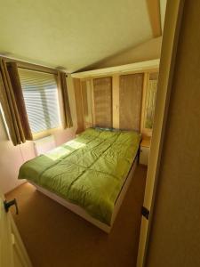 a bedroom with a green bed and a window at Summerlands, Ingoldmells 8 berth caravan in Skegness