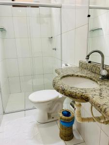 a white bathroom with a toilet and a sink at Pousada Corais Do Sul in Caraíva