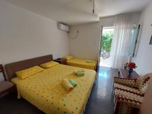 1 Schlafzimmer mit 2 Betten mit gelber Bettwäsche und einem Fenster in der Unterkunft Apartments Ivana in Ulcinj