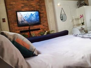 um quarto com uma cama e uma televisão numa parede de tijolos em Craftsmen's ship Maboneng, Apartment em Joanesburgo