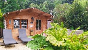 a small wooden cabin with two chairs in front of it at Manoir Desnachez in Taupont