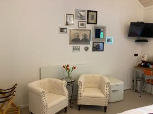 ein Wohnzimmer mit zwei Sesseln und einem Fernseher in der Unterkunft Bed and Breakfast Klein Beek in Hilvarenbeek