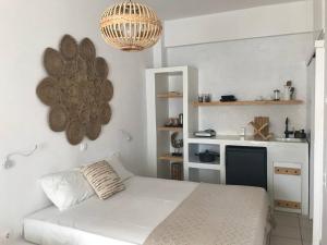 a white bedroom with a bed and a kitchen at Morpheus Rooms in Kini