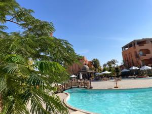 een zwembad in een resort met een palmboom bij Dream Lagoon Resort & Aqua Park in Marsa Alam
