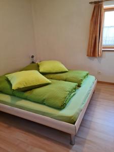 a bed with green sheets and yellow pillows on it at Lumpaz in Santa Maria Val Müstair