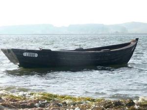 un barco sentado en el agua cerca de la orilla en Ruegen_Fewo 63, en Garz