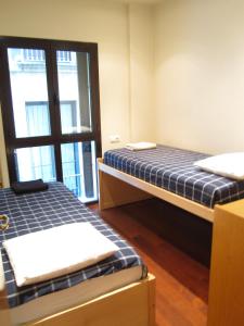 two beds in a room with a window at Olles Apartment in Barcelona