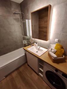 een badkamer met een wastafel, een spiegel en een bad bij Apartamenty 5.0 in Wołomin