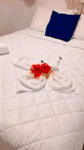 ein weißes Bett mit einer roten Blume drauf in der Unterkunft Pousada Corais Do Sul in Caraíva