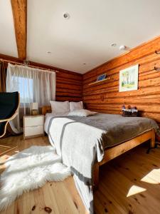 1 dormitorio con 1 cama grande en una pared de madera en Jūras Pērle en Tūja