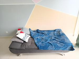 a couch with a blue blanket and pillows on it at Medini Signature x 3min to Legoland x 2BR x 7pax in Nusajaya