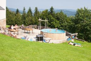 Eine Gruppe von Menschen lag auf dem Rasen neben einem Pool. in der Unterkunft Swoboda na szczycie góry z dala od miasta in Brenna