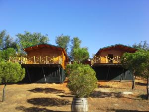 Duas cabanas com árvores à frente. em Arroyo de Carboneras em Brazatortas