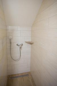 y baño de azulejos blancos con ducha y manguera. en APARTMAJI HUBI, en Bled