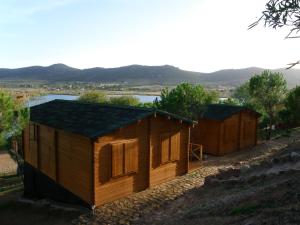 um grupo de cabanas de madeira numa colina com um lago em Arroyo de Carboneras em Brazatortas