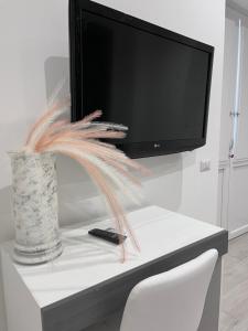 a tv sitting on top of a table with a vase at GLAM B&B room in San Giuseppe Vesuviano