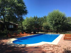 a swimming pool with chairs and a house at Cabañas Los Maderos in Villa General Belgrano