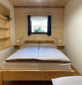 Cama en habitación pequeña con ventana en Apartma Korošec, en Srednja Vas v Bohinju