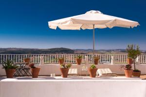 eine Terrasse mit einem Sonnenschirm, Stühlen und Topfpflanzen in der Unterkunft Casa Boutique Encalada in Vejer de la Frontera