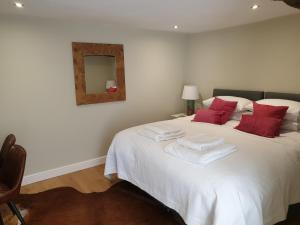 a bedroom with a white bed with red pillows and a mirror at Trouble House in Tetbury