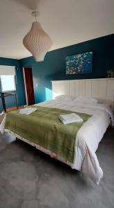 a large bed in a bedroom with a blue wall at La Azul in Dina Huapi