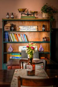 uma mesa e cadeiras em frente a uma estante de livros em Dawna Apteka Old Pharmacy em Wydminy