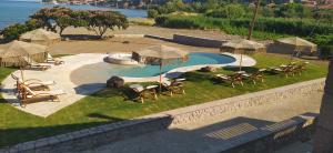 a pool with chairs and umbrellas in a yard at Michaela Beach Houses in Mythimna