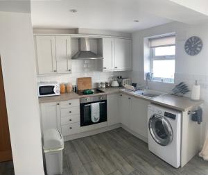 uma cozinha com armários brancos e uma máquina de lavar roupa em Taitwt 3 em Caernarfon