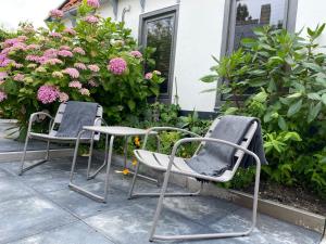 two chairs sitting on a patio with flowers at Ambiance in Hollum