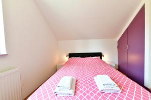 1 dormitorio con 1 cama rosa y 2 toallas en Apartment Anna Maria, en Rakovica