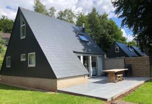una casa nera con un tavolo da picnic di fronte di Le Cottage du Raidillon a Malmedy