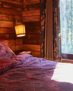 a bedroom with a bed with a lamp and a window at Tiny House Cetturu - 2-pers luxe en romantisch boshuisje in Houffalize