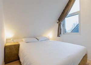 una camera da letto con un grande letto bianco con una finestra di Le Cottage du Raidillon a Malmedy
